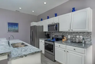 a kitchen with white cabinets and granite counter tops at Spacious 4BR Home Themed Rooms, Pool, Near Disney in Orlando