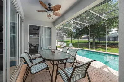 a patio with a table and chairs and a pool at Spacious 4BR Home Themed Rooms, Pool, Near Disney in Orlando