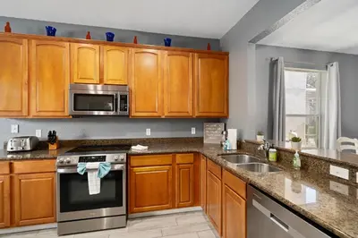 a kitchen with wooden cabinets and stainless steel appliances at Luxury 5BR Villa Near Disney, Private Pool & Game Room in Orlando