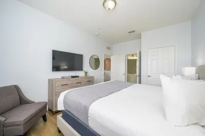 a bedroom with a bed and a chair and a television at New Listing Beautiful Condo, Vista Cay - 3017 in Orlando