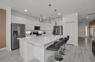 a kitchen with a white counter and black chairs at American Secret 10 BED 7 Miles to Disney in Kissimmee