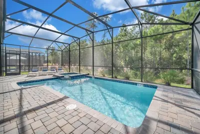 a swimming pool in a glass house with a patio at Storey Lake 9 BR Villa With Games Room and Theater home in Kissimmee