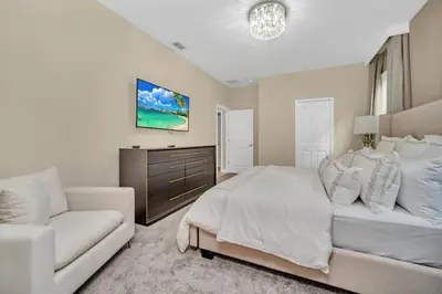 a bedroom with a white bed and a couch at Storey Lake 9 BR Villa With Games Room and Theater home in Kissimmee