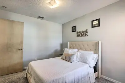a bedroom with a bed with white sheets and pillows at Less Than 8 Mi to Disney Getaway with Deck in Kissimmee! in Kissimmee