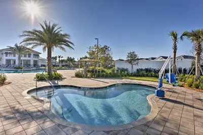 a swimming pool with a slide and palm trees at 6 Mi to Disney Resort Hideaway with Pool Access! in Kissimmee