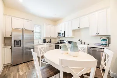 a kitchen with white cabinets and a white table and chairs at Mango Breeze Cottage With Private Pool Near Disney With Margaritaville Resort And Island H20 Waterpark Access - 2910Sr in Orlando