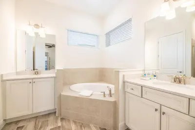 a white bathroom with a tub and a sink at Blue Sky Cottage Near Disney With Private Pool & Margaritaville Resort And Island H20 Waterpark Access - 2912Sr in Orlando