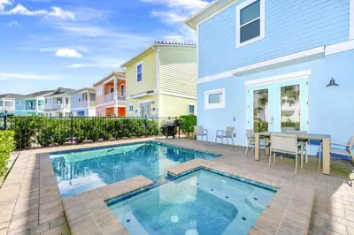 a pool with a table and chairs next to a house at Charming Cottage Near Disney With Margaritaville Resort & Island H20 Waterpark Access - 2918Sr in Orlando