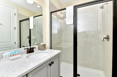 a bathroom with a sink and a glass shower at Jamaican Spice Cottage Near Disney With Margaritaville Resort & Island H20 Waterpark Access - 2924Sr in Orlando