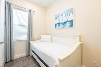 a small bedroom with a bed and a window at Refreshing Blue Cottage Near Disney With Margaritaville Resort & Island H20 Waterpark Access - 2942Sr in Orlando