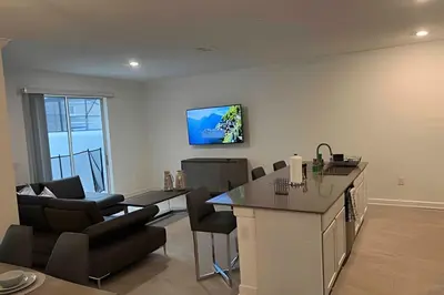 a kitchen and living room with a counter and chairs at Storey Lake home close to Disney and other parks in Kissimmee