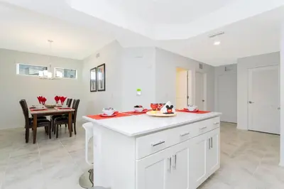 a kitchen with white cabinets and a dining room with a table at Gorgeous 3Bd 8 Guests @Storey Lake Resort Close to Disney 101 3191 in Kissimmee