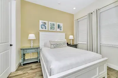 a bedroom with a white bed and two tables with lamps at Peachy Dream Cottage With Private Pool Near Disney And Margaritaville Resort &Land H2O Access - 8016Kd in Orlando
