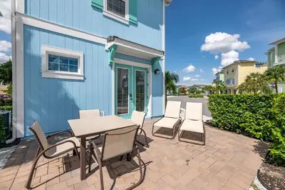 a patio with a table and chairs next to a blue building at Sky Blue Cottage Near Disney With Margaritaville Resort & Island H2O Access - 8012Ff in Orlando