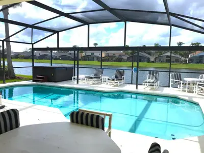 a large swimming pool with chairs and a table at Sunny South Facing Pool with Hot Tub and Lake View Near Disney in Kissimmee