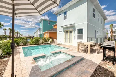 a swimming pool with an umbrella next to a house at Sunset Dream Cottage With Private Pool Near Disney With Margaritaville Resort & Island H2O Access - 8029Kd in Orlando