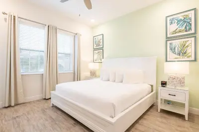 a white bedroom with a bed and a window at Cozy Peach Cottage Near Disney With Margaritaville Resort & Island H2O Access - 8029Dr in Orlando