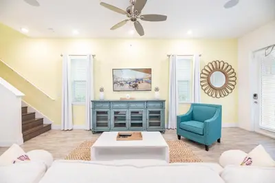 a living room with a couch and a blue chair at Cozy Peach Cottage Near Disney With Margaritaville Resort & Island H2O Access - 8029Dr in Orlando