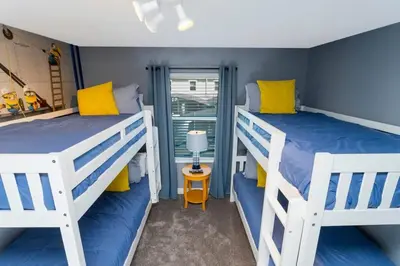 two bunk beds in a room with blue walls and yellow pillows at Gorgeous 4 Bd w/ Pool Close to Disney @ Storey Lake 2963 in Kissimmee