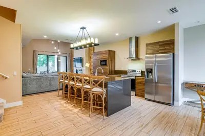 a kitchen with a bar with stools and a refrigerator at Magic Villas Townhome about 5 Mi to Disney Parks! in Orlando