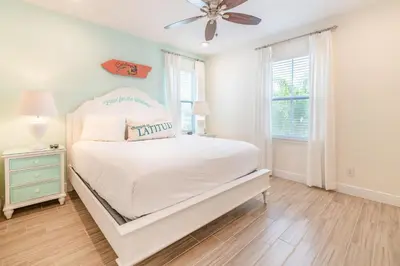 a white bedroom with a bed and a ceiling fan at Sunburnt Cottage With Hot Tub Near Disney With Margaritaville Resort & Island H2O Access - 8041Sh in Orlando