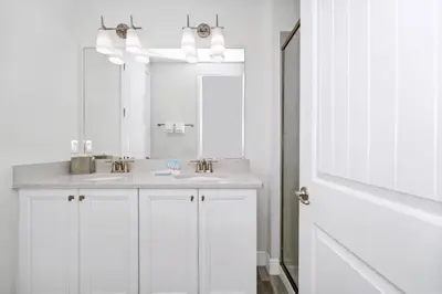 a white bathroom with two sinks and a mirror at Dreamy Cottage With Private Pool Near Disney With Margaritaville Resort & Island H2O Access - 8082Kd in Orlando