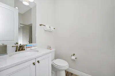 a white bathroom with a toilet and a sink at Dreamy Cottage With Private Pool Near Disney With Margaritaville Resort & Island H2O Access - 8082Kd in Orlando