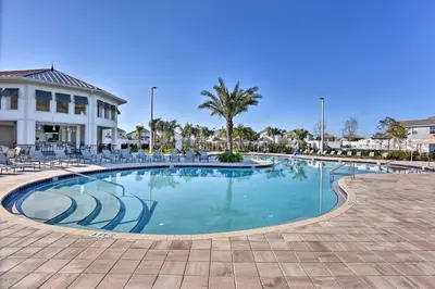 a large swimming pool with chairs and a building at 5 Mi to Disney Chic Townhome with Community Perks! in Kissimmee