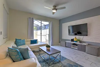 a living room with a couch and a flat screen tv at 5 Mi to Disney Chic Townhome with Community Perks! in Kissimmee
