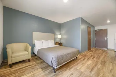 a bedroom with a bed and a chair at WoodSpring Suites Orlando I-4 & Convention Center in Orlando
