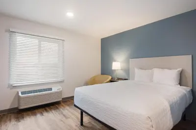a bedroom with a white bed and a window at WoodSpring Suites Orlando I-4 & Convention Center in Orlando