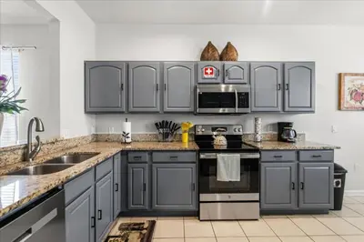 a kitchen with gray cabinets and stainless steel appliances at Disney Vacation Oasis Pool BBQ Resort Fun in Orlando
