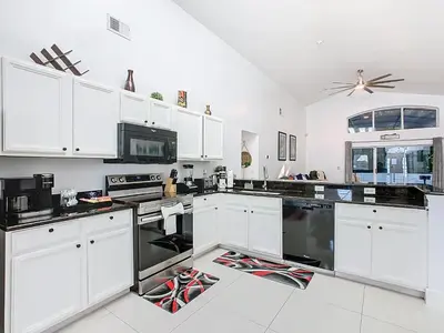 a kitchen with white cabinets and black appliances at Casita mi Encanto a Cozy & Spacious House, 4-bedroom 3-Bath & pool in Kissimmee