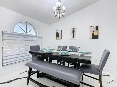 a dining room with a black table and chairs at Casita mi Encanto a Cozy & Spacious House, 4-bedroom 3-Bath & pool in Kissimmee