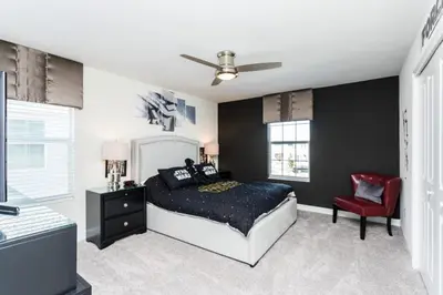 a bedroom with a bed and a red chair at 5 bedroom home is ideal for an elegant vacation villa in Kissimmee