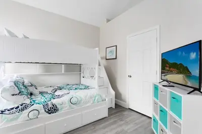 a white bedroom with a bed and a flat screen tv at Amazing 6 Bed Disney Dream Getaway in Windsor Palm villa in Kissimmee