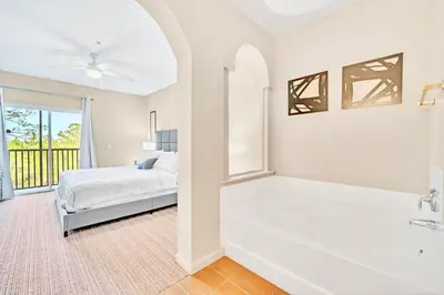 a white bathroom with a tub and a bed at Bright 2BR Condo with Pool - near Disney! in Orlando