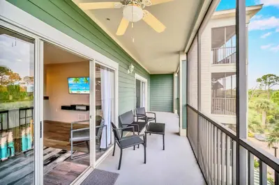 a balcony with chairs and a table and a tv at Bright 2BR Condo with Pool - near Disney! in Orlando