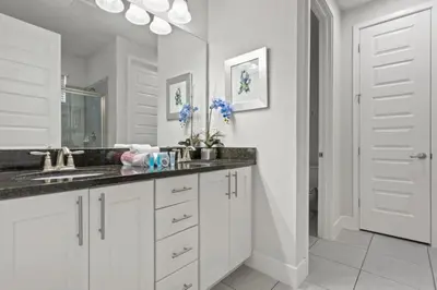 a white bathroom with a sink and a mirror at 360 Pendant Ct · 360 Villa - 7BD - Pool Theme Beds by Disney in Orlando