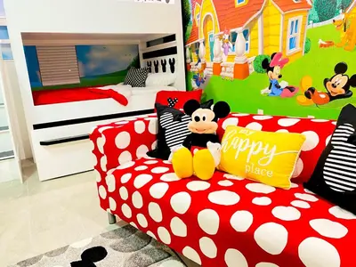 a room with a red couch with a mickey mouse pillow at Happiest House on Earth near Disney World 9 Bedroom, Pool, Theater, Gameroom, Mickey Bunk room with Twisty Slide in Storey Lake in Kissimmee