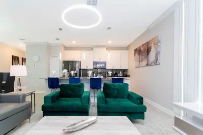 a living room with two green chairs and a kitchen at Gorgeous 4 Bd Close to Disney w/ Pool @ Storey Lake Resort 4245 in Kissimmee