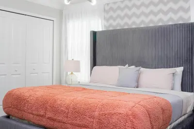 a bedroom with a large bed with a orange blanket at Gorgeous 4 Bd Close to Disney w/ Pool @ Storey Lake Resort 4245 in Kissimmee