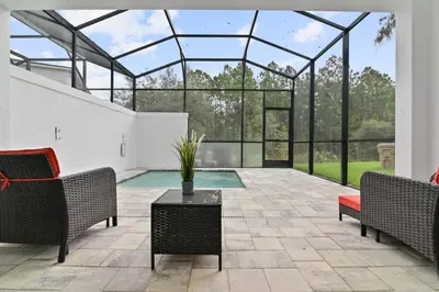 a conservatory with a pool and two chairs and a table at New Cozy & Spacious Townhouse near Disney - 4BR, 3FB, and Pool in Orlando