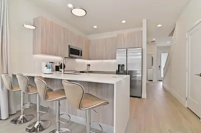 a kitchen with a counter with stools and a refrigerator at New Cozy & Spacious Townhouse near Disney - 4BR, 3FB, and Pool in Orlando