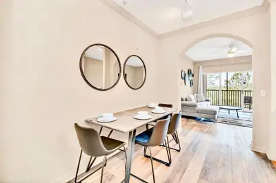 a dining room with a table and chairs and a mirror at 2BR Condo with shared Pool near Disney! in Orlando