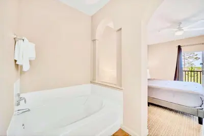 a white bathroom with a tub and a bed at 2BR Condo with shared Pool near Disney! in Orlando