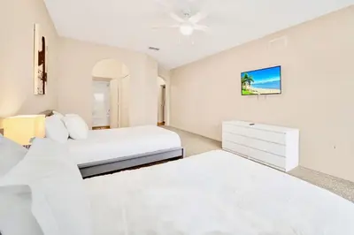 a white bedroom with two beds and a dresser at 2BR Condo with shared Pool near Disney! in Orlando