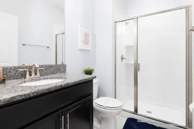 a bathroom with a toilet and a sink and a shower at Storey Lake Pool Mins to Disney 4BR Games in Kissimmee