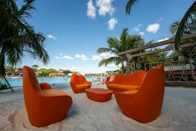 a group of orange chairs sitting on the sand near a pool at Evermore Orlando Resort in Orlando
