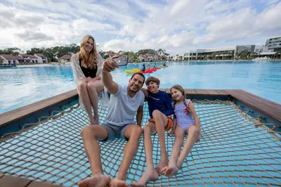 a man and two girls sitting on the edge of a swimming pool at Evermore Orlando Resort in Orlando